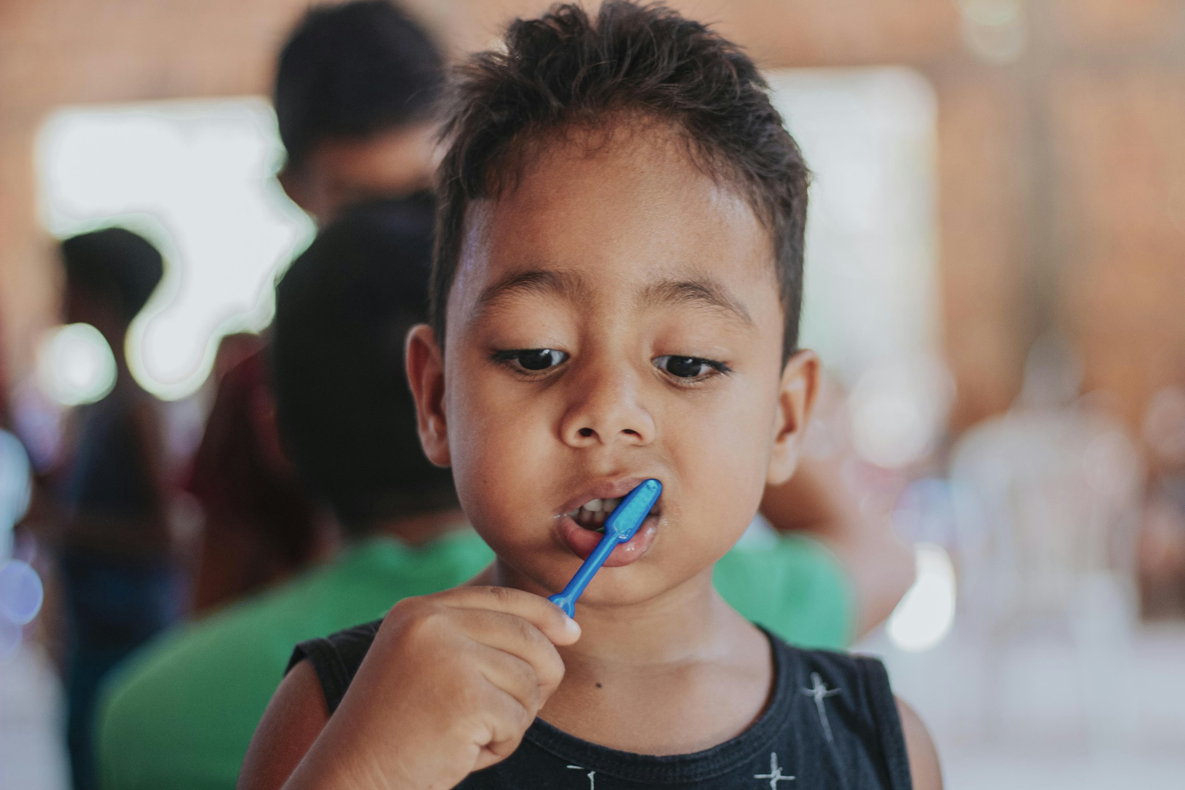 A boy brushing his teeth with a blue toothbrush