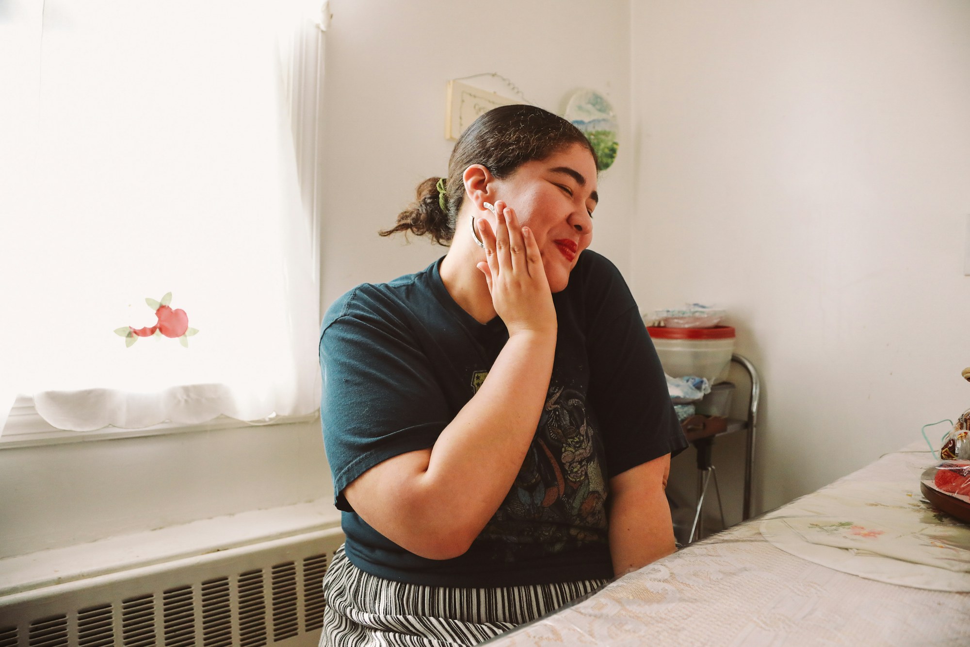 A woman at a kitchen window holding her cheek