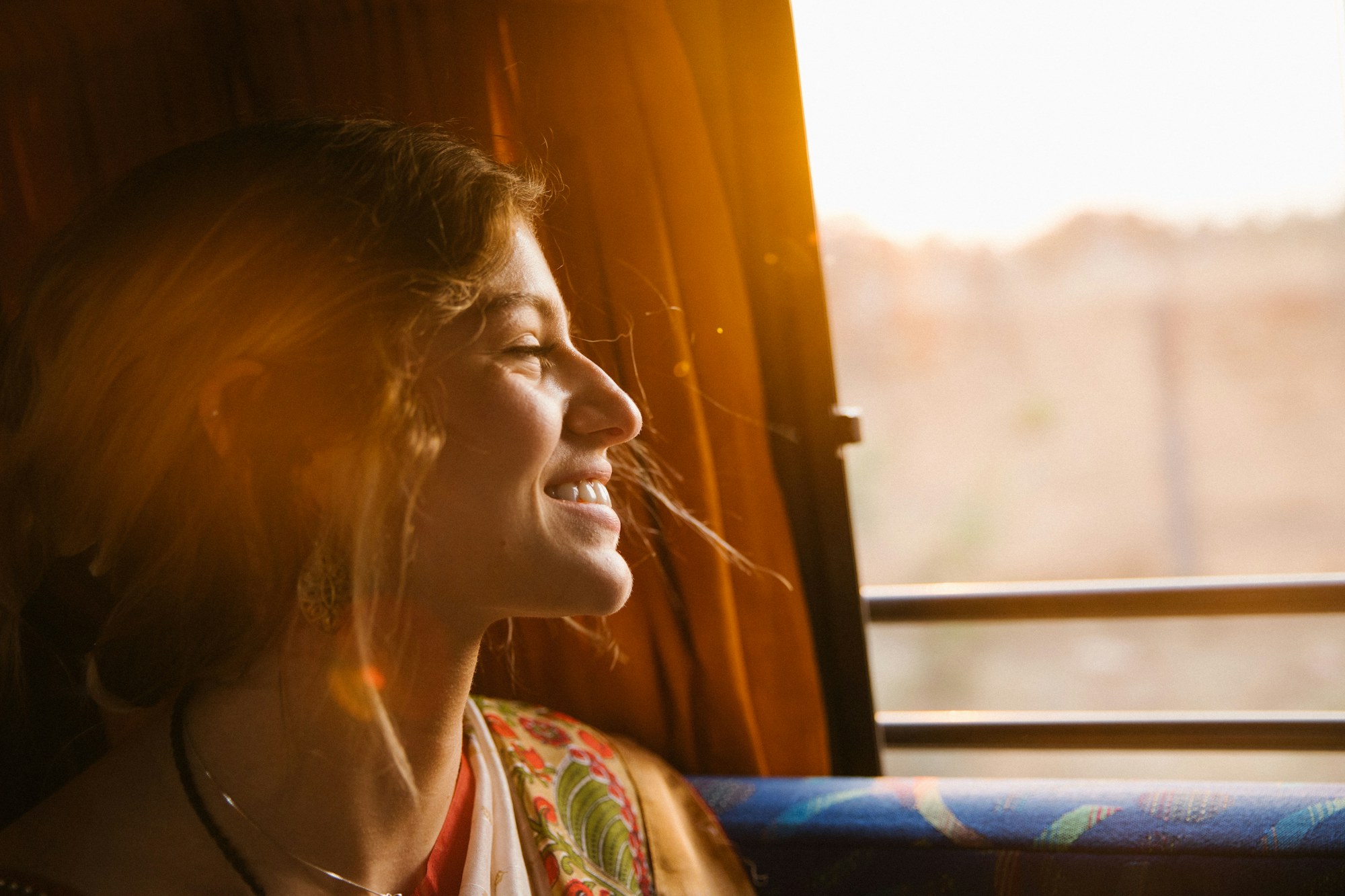 A woman smiling in the evening sun by a window