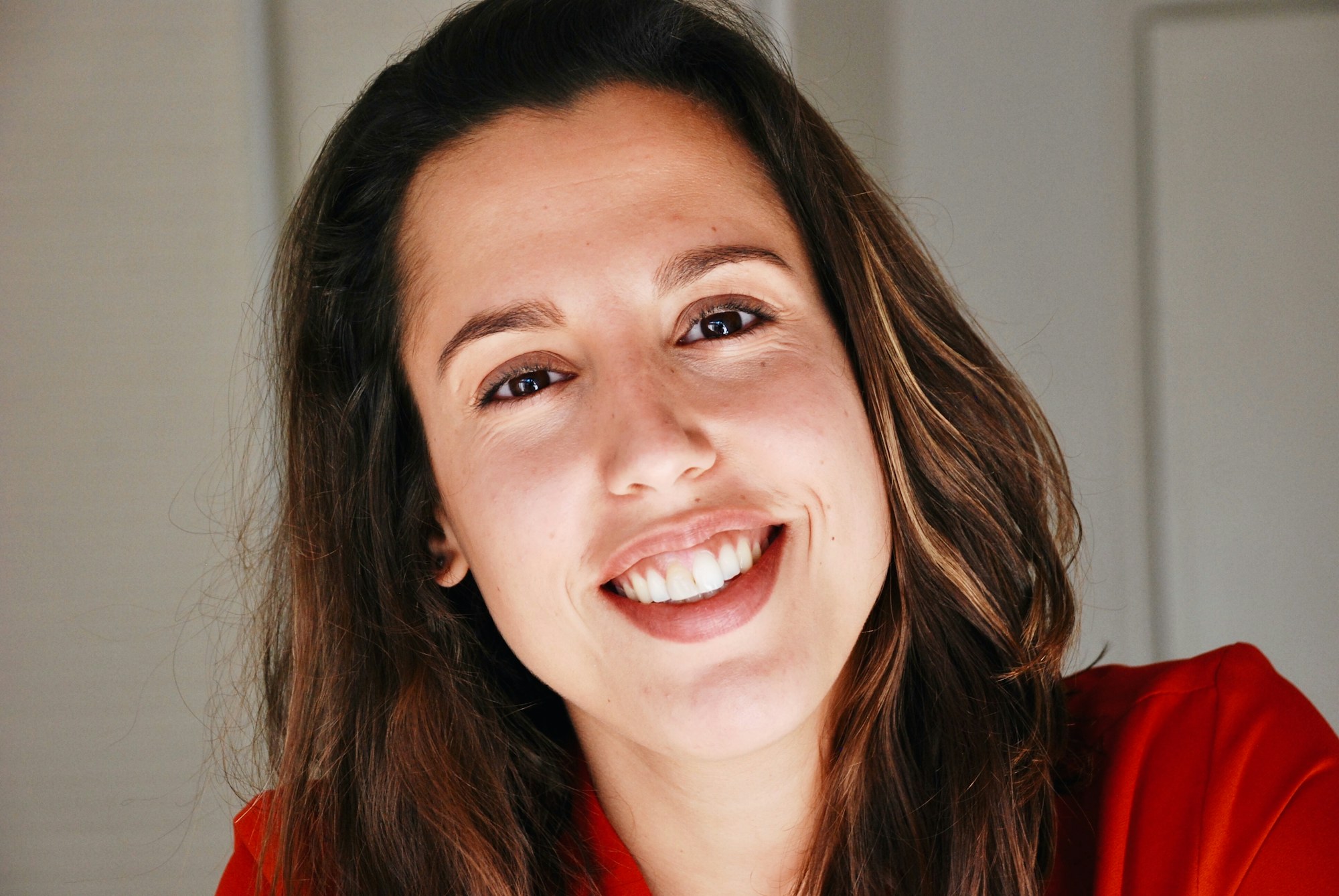 A woman in a red top smiling broadly