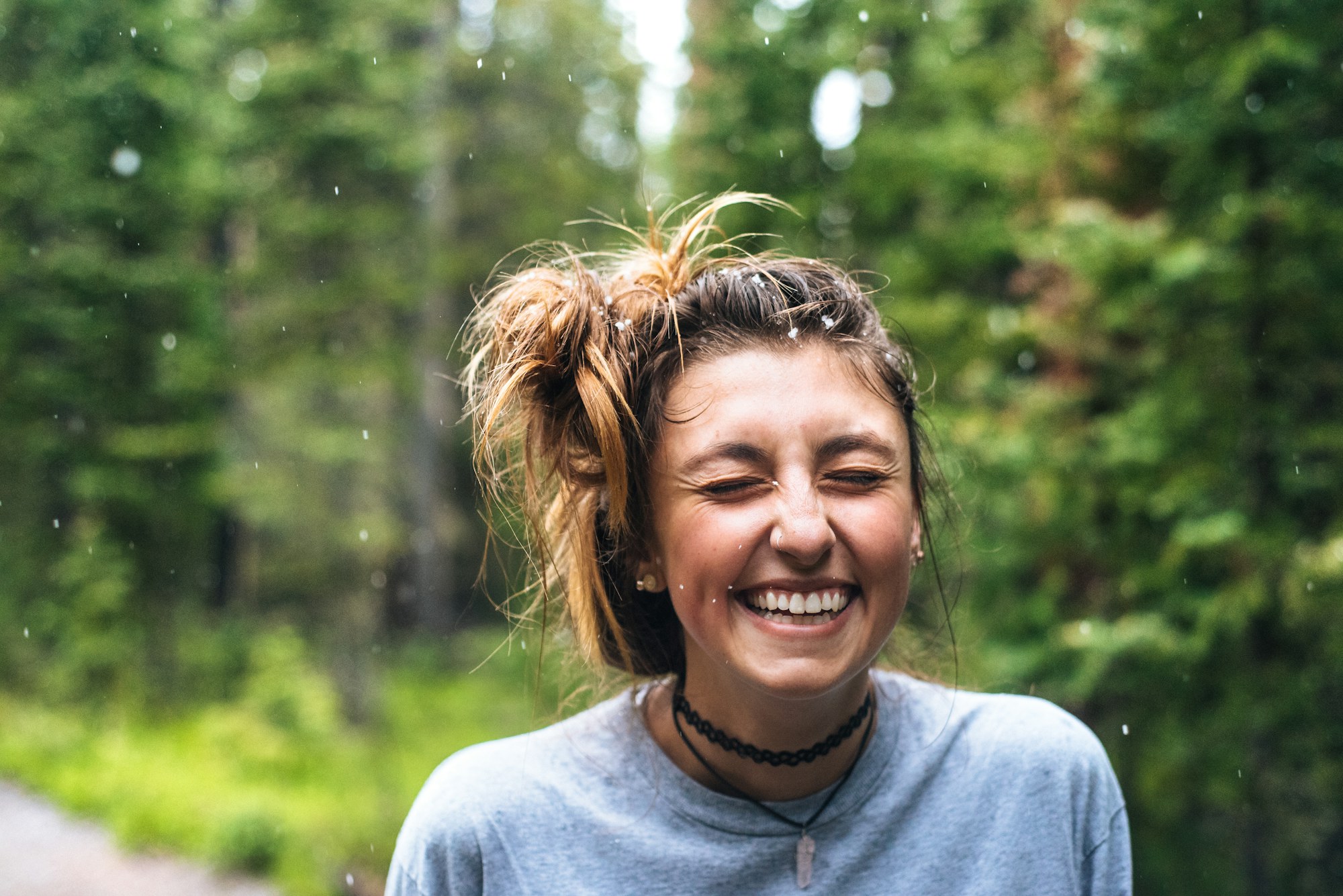 A woman laughing among trees in daylight